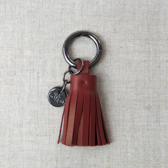 Key holder and bag charms TASSEL in lambskin bordeaux color and shiny gun finishing - front view - linen background