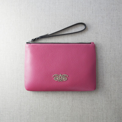 SUZY, grained leather zipper pouch in pink raspberry with black wrist strap - on linen