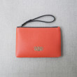 SUZY, grained leather zipper pouch in red hibiscus color with black wrist strap - on linen