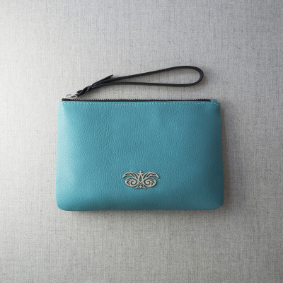 SUZY, grained leather zipper pouch in turquoise color with black wrist strap - on linen