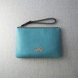 SUZY, grained leather zipper pouch in turquoise color with black wrist strap - on linen