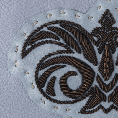 La pochette zippée en cuir "OSLO BRODÉE" coloris gris-lavande avec un logo noir vintage - broderie cannetille